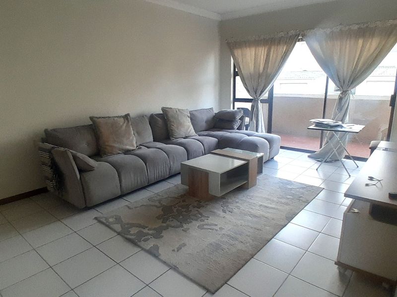 A living room featuring tiled flooring and a sliding glass door providing access to an outdoor balcony area.