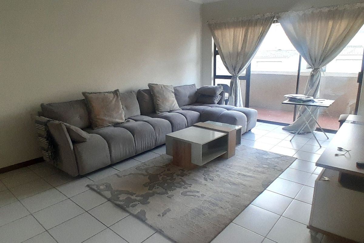 A living room featuring tiled flooring and a sliding glass door providing access to an outdoor balcony area.