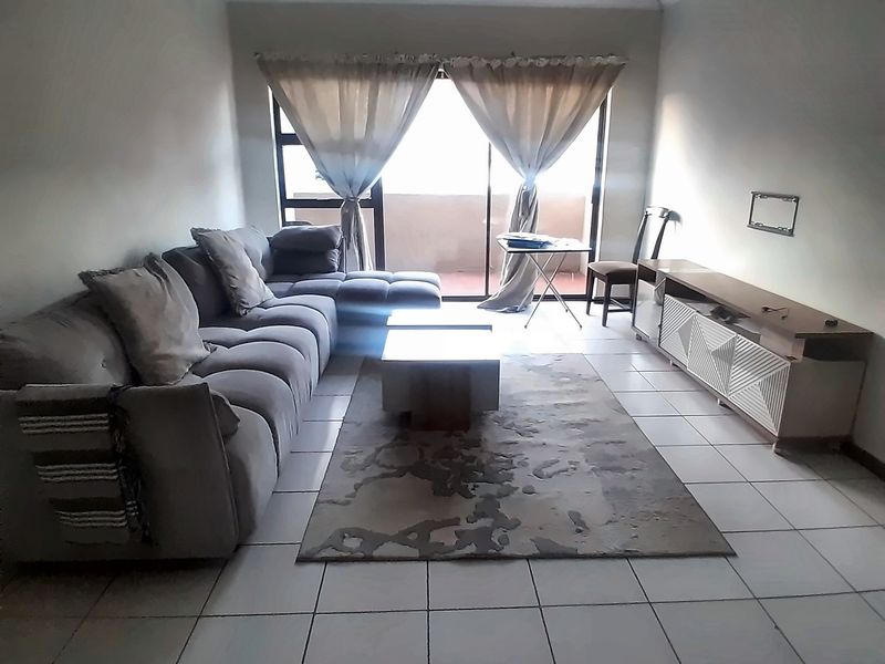 A living room featuring tiled flooring and a sliding glass door leading to an outdoor area, providing natural light to the space.