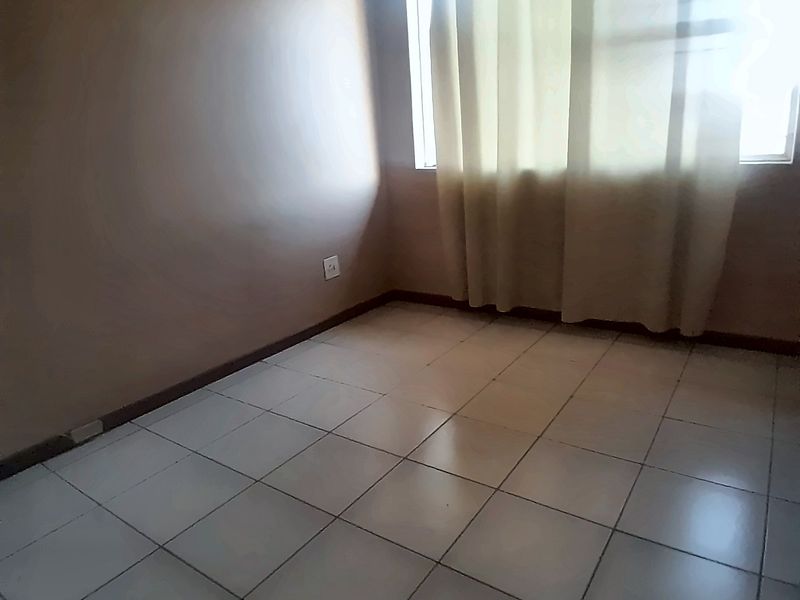 An empty bedroom featuring tiled flooring and neutral wall finishes, providing a blank canvas for personalization.