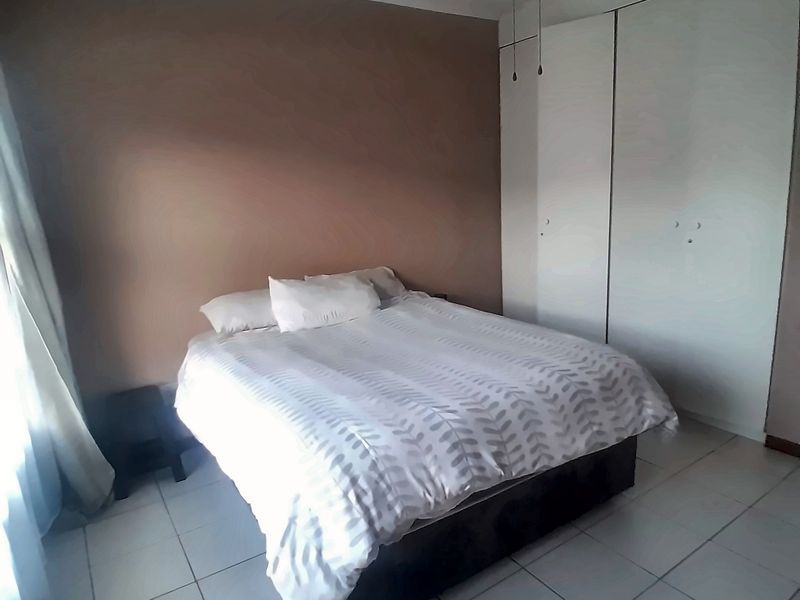 A bedroom featuring tiled flooring, built-in cupboards, and a ceiling fan.
