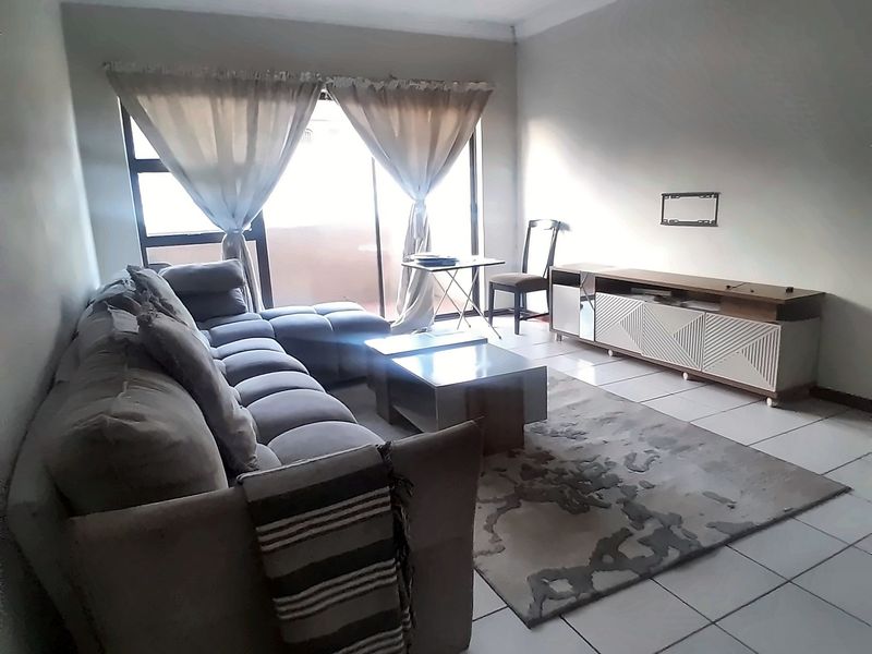 A living room featuring tiled flooring, a coved ceiling, and a sliding glass door providing access to an outdoor area.