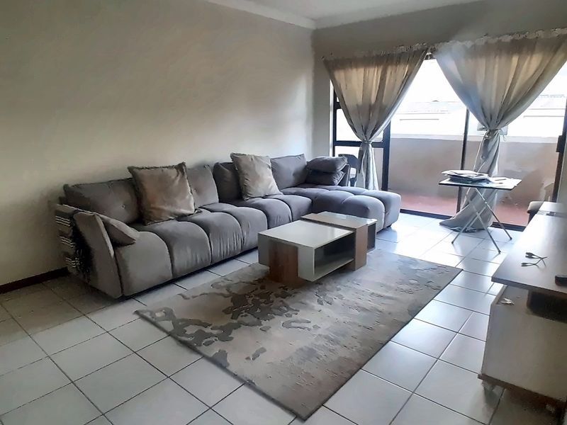 A living room featuring tiled flooring and a sliding glass door providing access to an outdoor balcony area.
