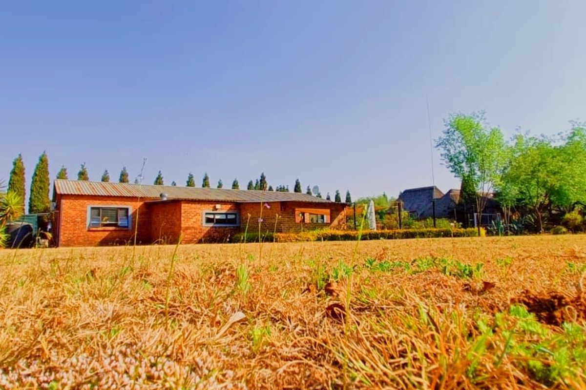 A view of the rear face brick house exterior featuring a tiled roof and established garden surroundings.