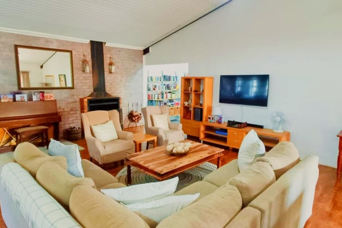 Spacious living room featuring a vaulted ceiling, laminate flooring, and a prominent exposed brick fireplace as a central focal point.