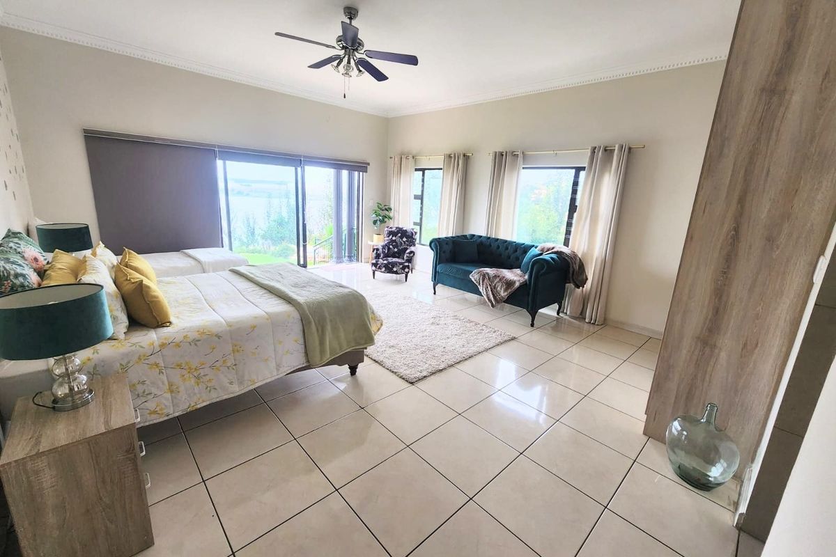 Spacious bedroom featuring tiled flooring, a ceiling fan, built-in wardrobe, and large sliding glass doors providing natural light and outdoor access.