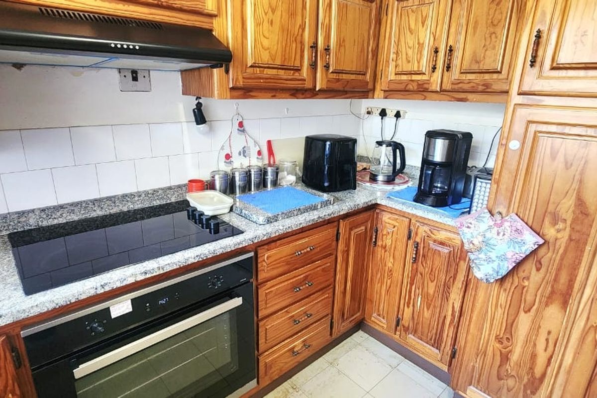 A functional kitchen featuring traditional wooden cabinetry, granite countertops, and integrated appliances, currently showing signs of age and wear.