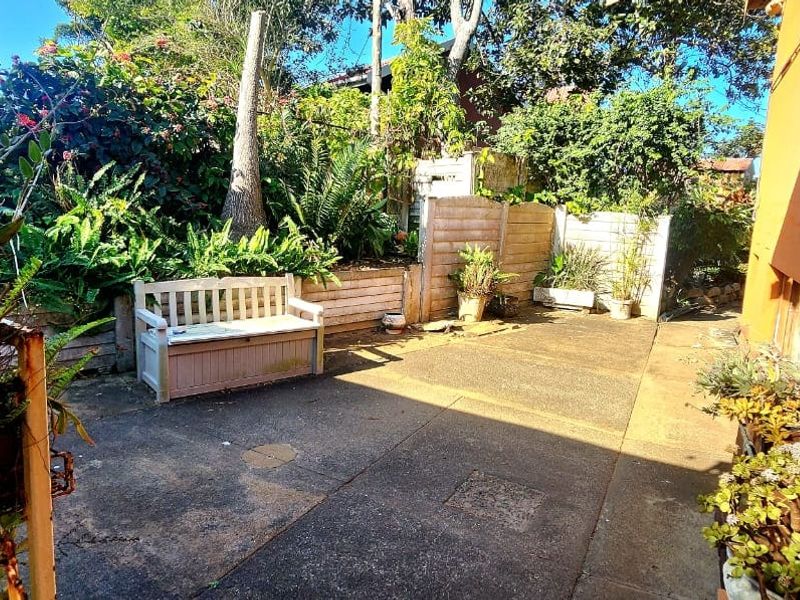 A rear exterior courtyard featuring concrete paving, a retaining wall, and timber fencing, offering a private outdoor space for relaxation.