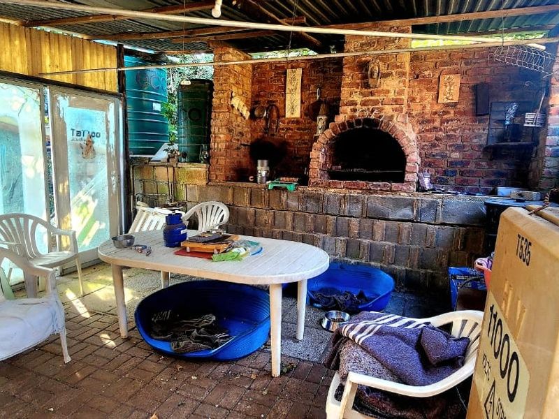 Covered outdoor patio area featuring a built-in brick pizza oven and braai, providing a rustic space for outdoor cooking and entertainment.