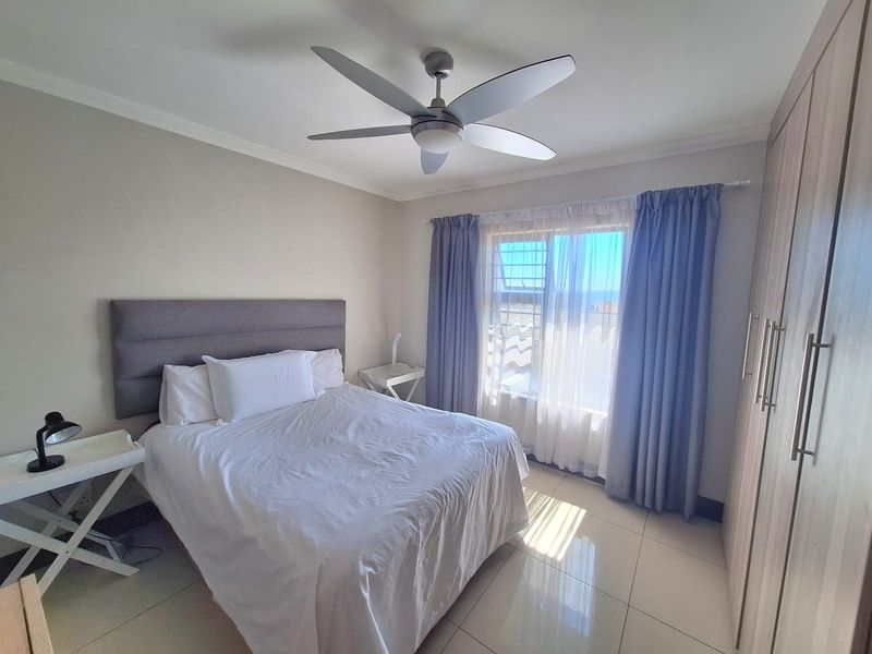 A well-maintained bedroom featuring tiled flooring, a ceiling fan, and built-in cupboards, offering a clean and functional living space.