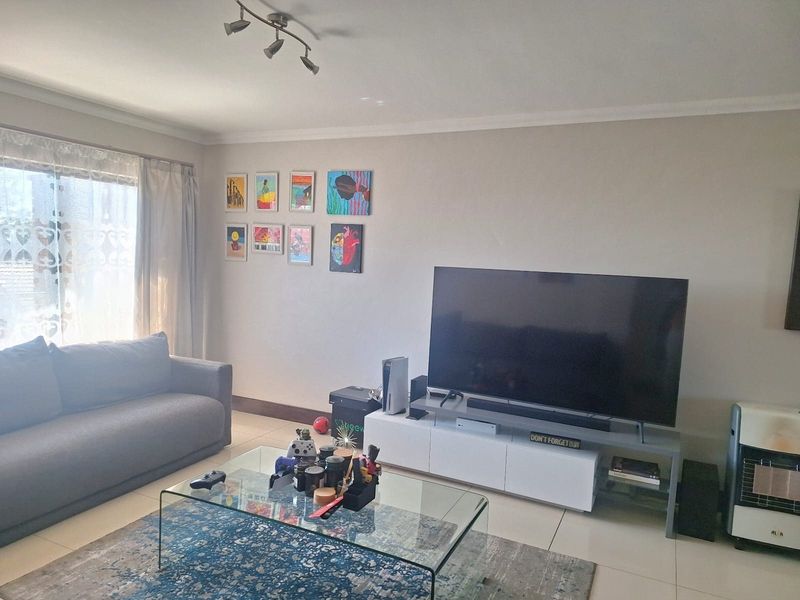 A well-lit living room featuring tiled flooring, coving, and a large sliding glass door providing natural light.