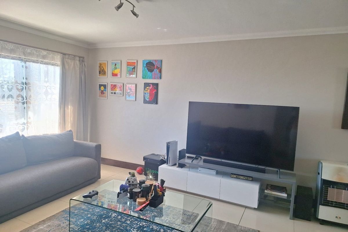 A well-lit living room featuring tiled flooring, coving, and a large sliding glass door providing natural light.