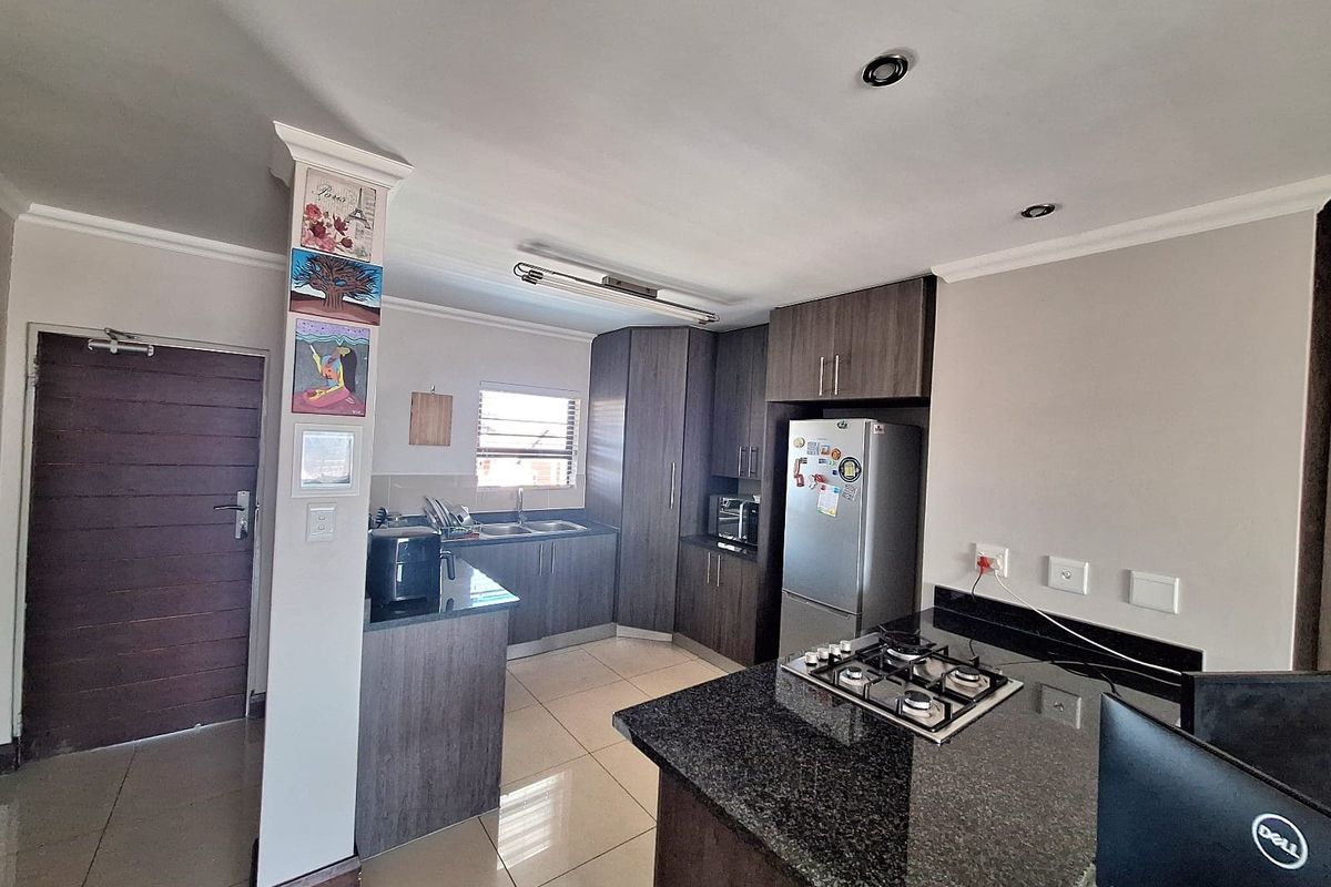 Modern kitchen featuring dark wood cabinetry, granite countertops, a gas hob, and tiled flooring, offering a functional and contemporary cooking space.
