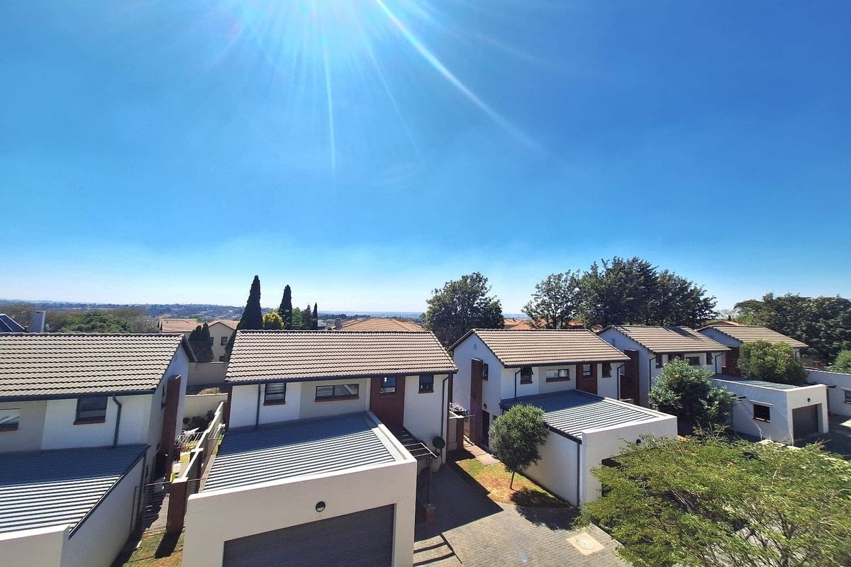 An elevated aerial view of a residential apartment complex featuring multiple units with tiled roofs, paved driveways, and garages.