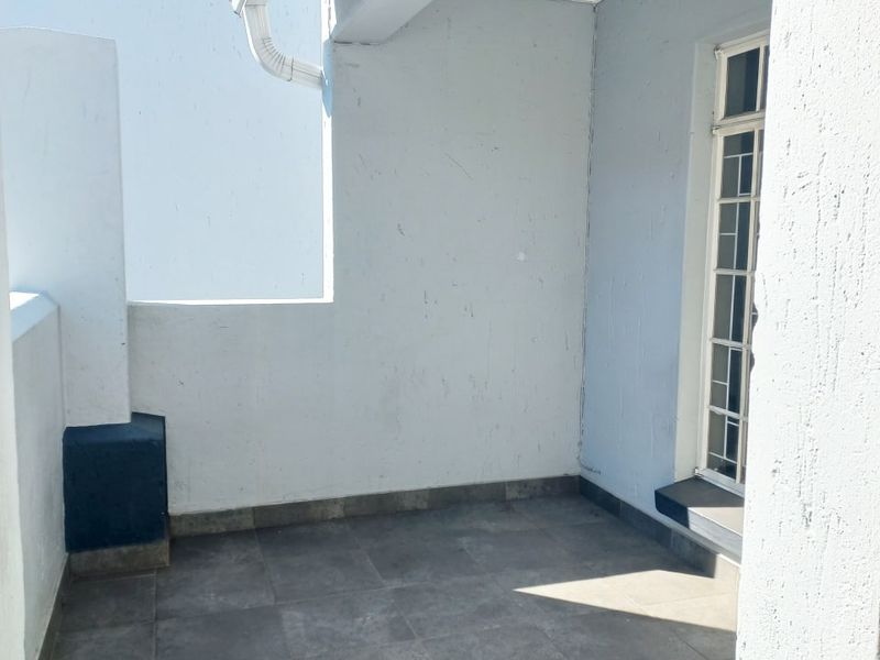 A clean, covered balcony area featuring neutral floor tiles and secure access, providing a functional outdoor space for the apartment.
