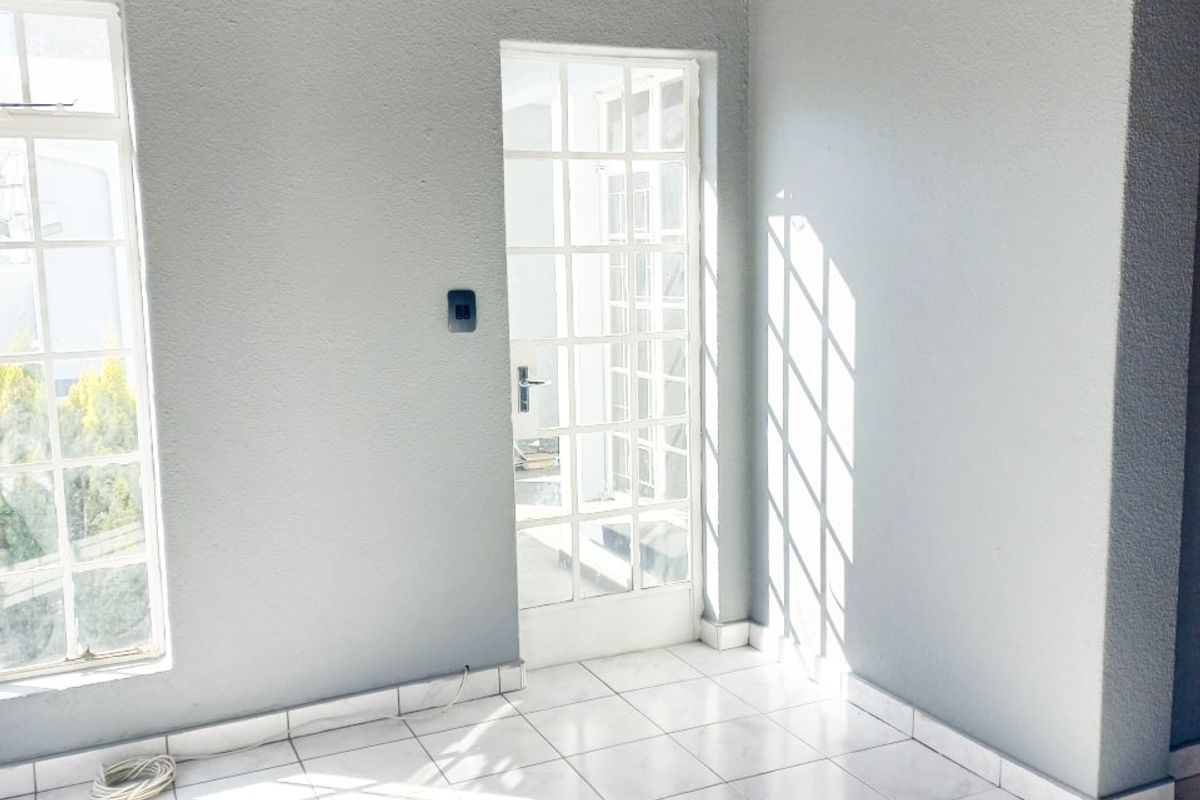 Bright and airy living space featuring tiled flooring, exposed timber ceiling beams, and direct access to the outdoors through a classic french door.