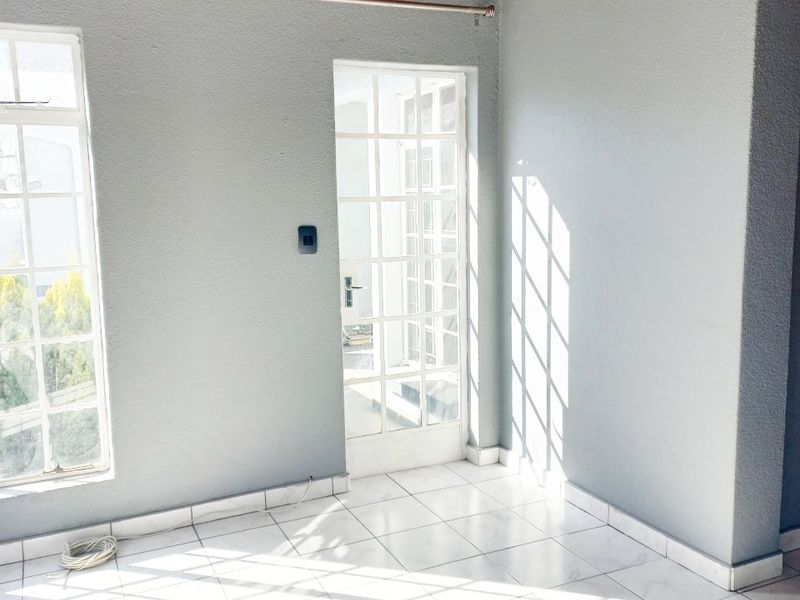 Bright and airy living space featuring tiled flooring, exposed timber ceiling beams, and direct access to the outdoors through a classic french door.