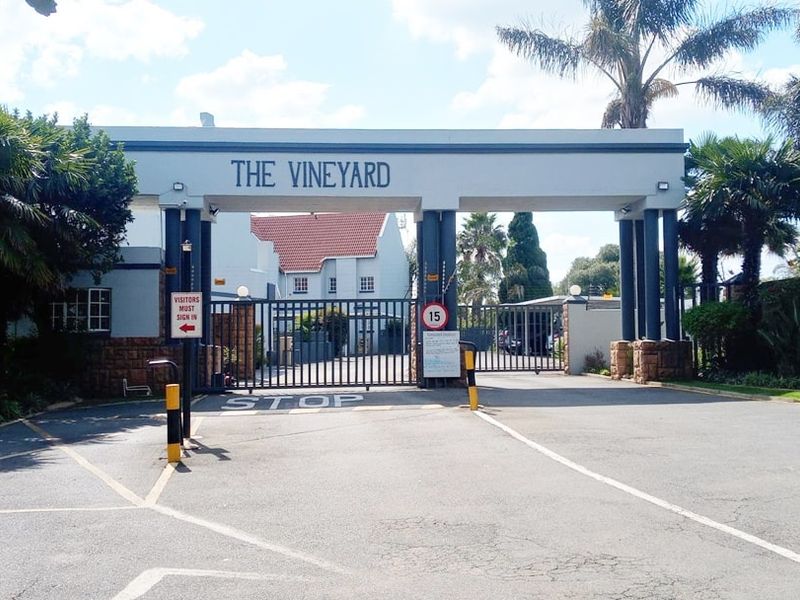 The secure gated entrance to The Vineyard apartment complex, featuring stone masonry pillars and a controlled access security gate.