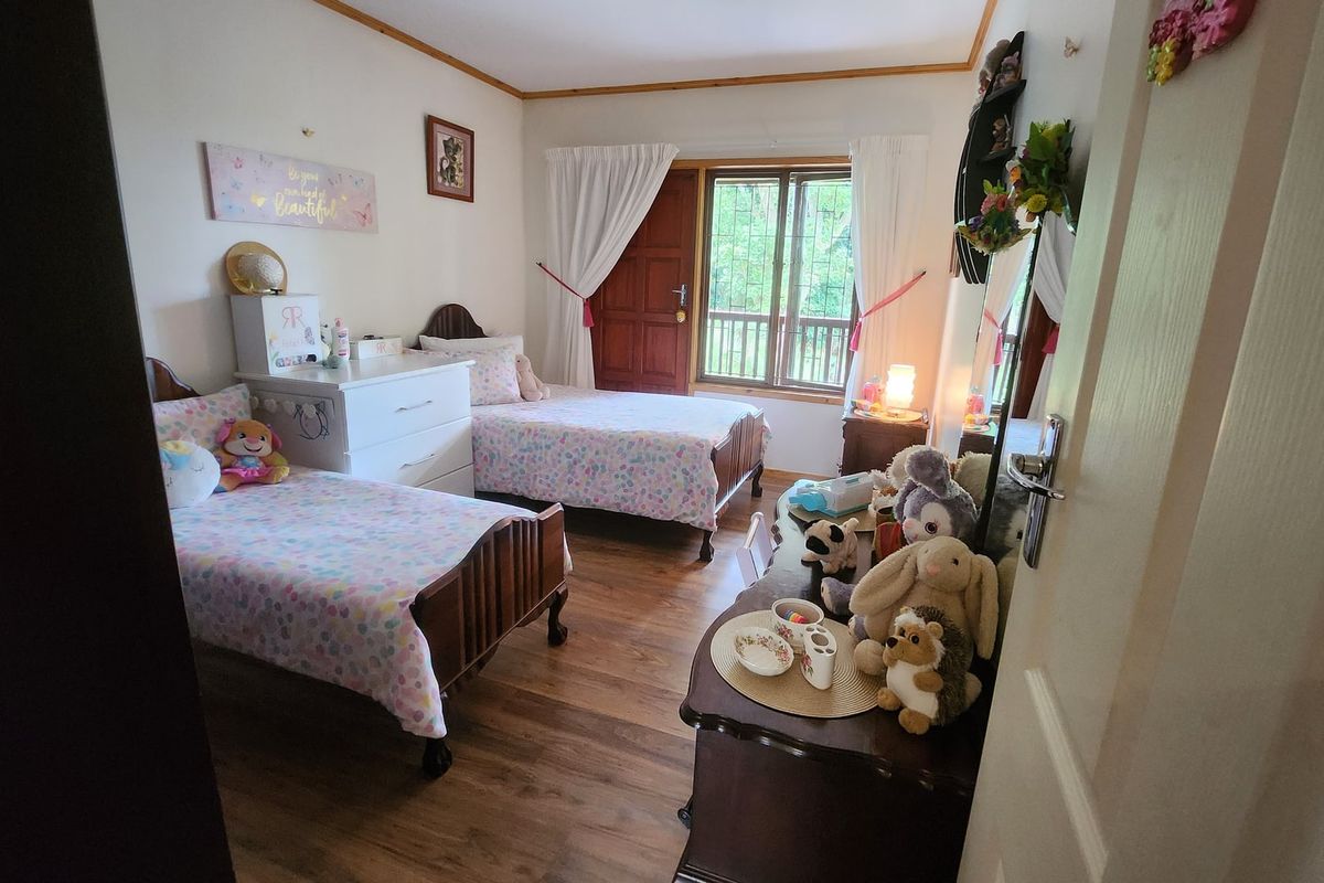 A bedroom featuring laminate flooring, a timber door, and a window with natural light.