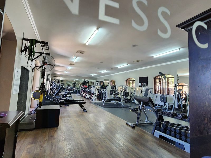 A well-maintained fitness center featuring laminate flooring, mirrored walls, and ample space for various exercise equipment.