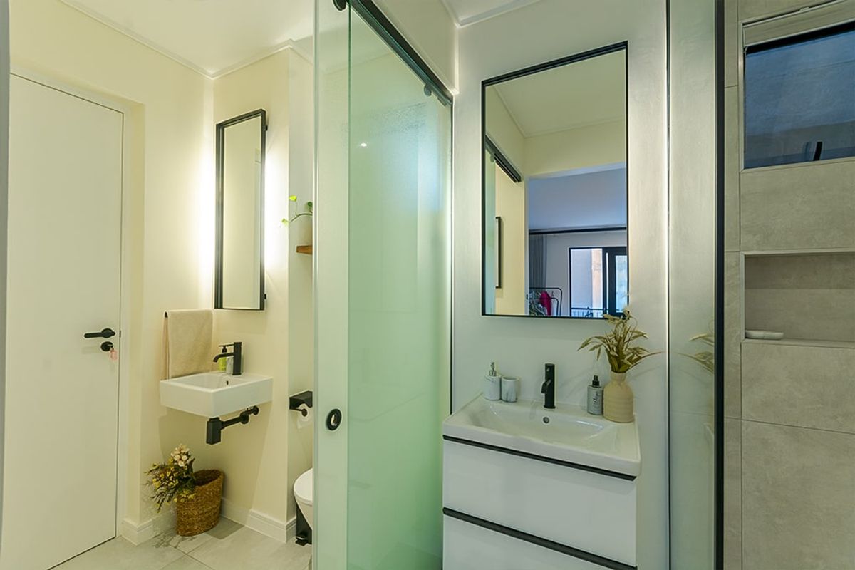 Modern bathroom featuring a wall-mounted vanity, glass shower enclosure, contemporary black tapware, and a recessed shower niche with neutral tiling.