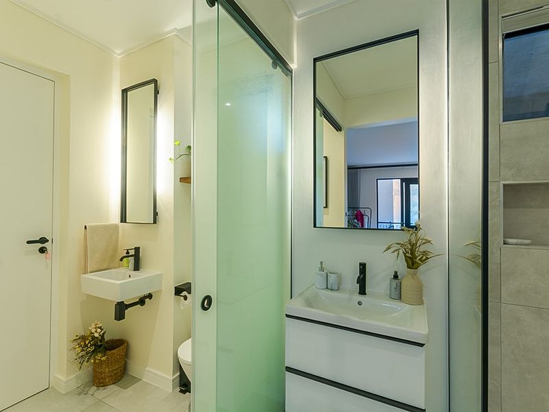 Modern bathroom featuring a wall-mounted vanity, glass shower enclosure, contemporary black tapware, and a recessed shower niche with neutral tiling.