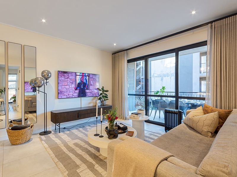A well-maintained living room featuring tiled floors, recessed lighting, and large sliding glass doors providing access to an adjoining balcony.