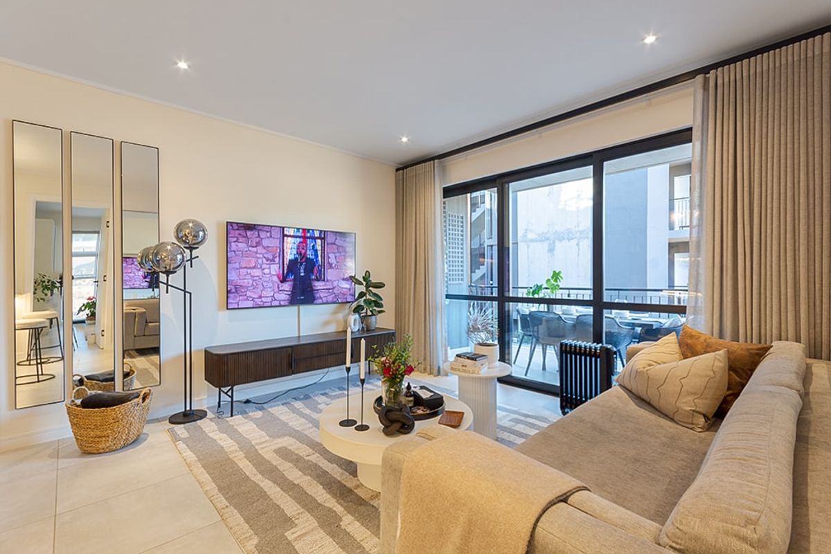 A well-maintained living room featuring tiled floors, recessed lighting, and large sliding glass doors providing access to an adjoining balcony.