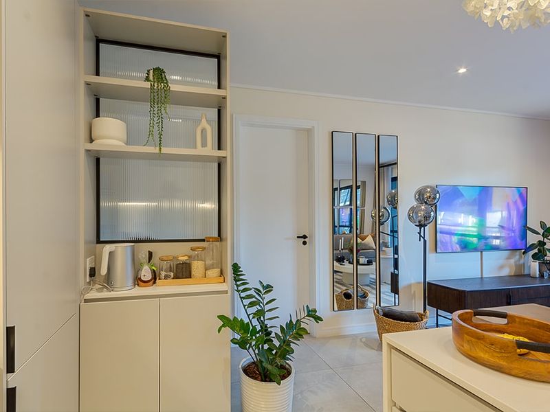 Modern open-plan living area featuring sleek built-in cabinetry with fluted glass shelving and neutral tiled flooring.