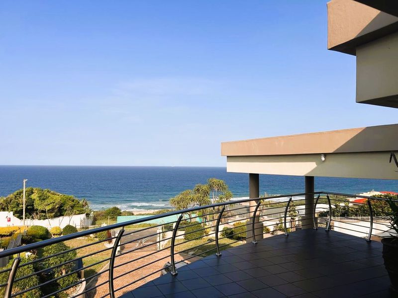 Spacious covered balcony featuring tiled flooring and a modern stainless steel balustrade, offering expansive, unobstructed views of the ocean.