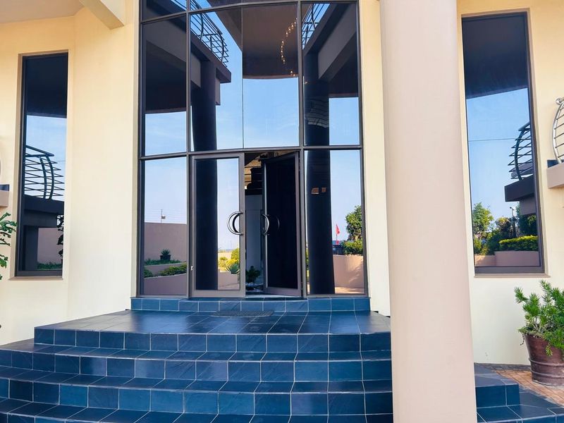 Grand entrance featuring a double-height glass facade and tiled steps, providing a modern and welcoming approach to the property.