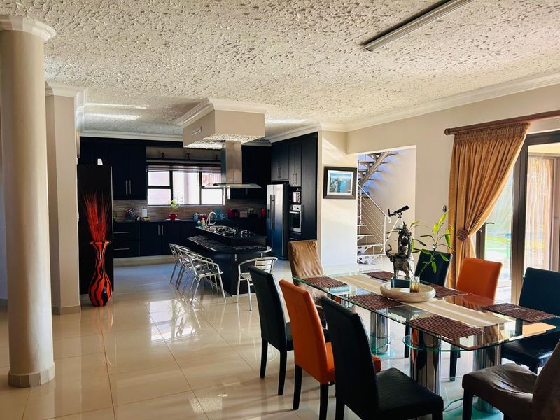 Spacious open-plan living and dining area featuring a modern kitchen with dark cabinetry, a central island, and direct access to the outdoor patio.