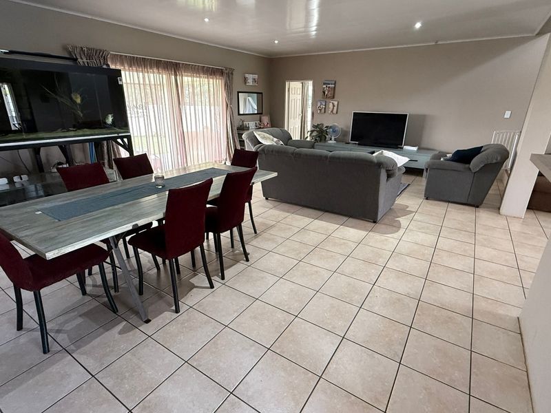 Spacious open-plan living and dining area featuring neutral ceramic floor tiles, recessed ceiling lighting, and large sliding glass doors providing access to the exterior.