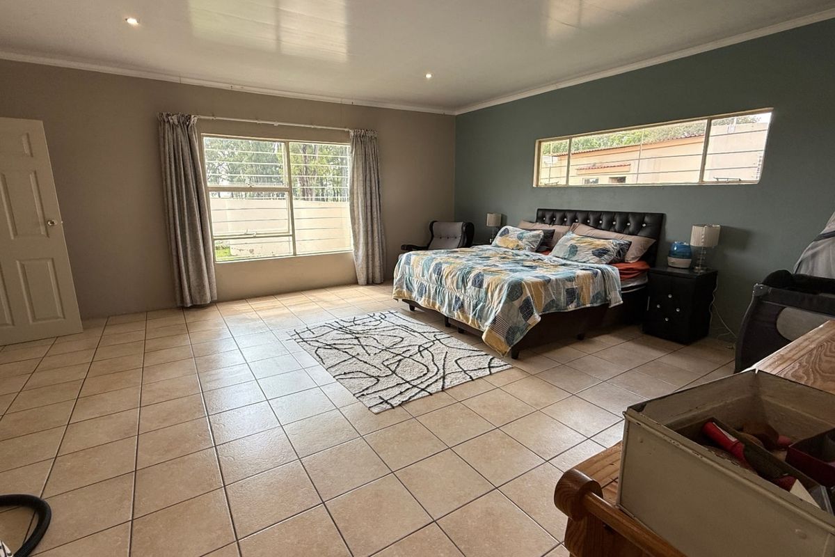 Spacious bedroom featuring large windows with security bars, tiled flooring, and a neutral color palette.