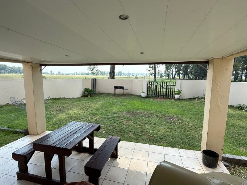 A covered patio area with tiled flooring overlooking a private, enclosed garden with perimeter walling and rural views.