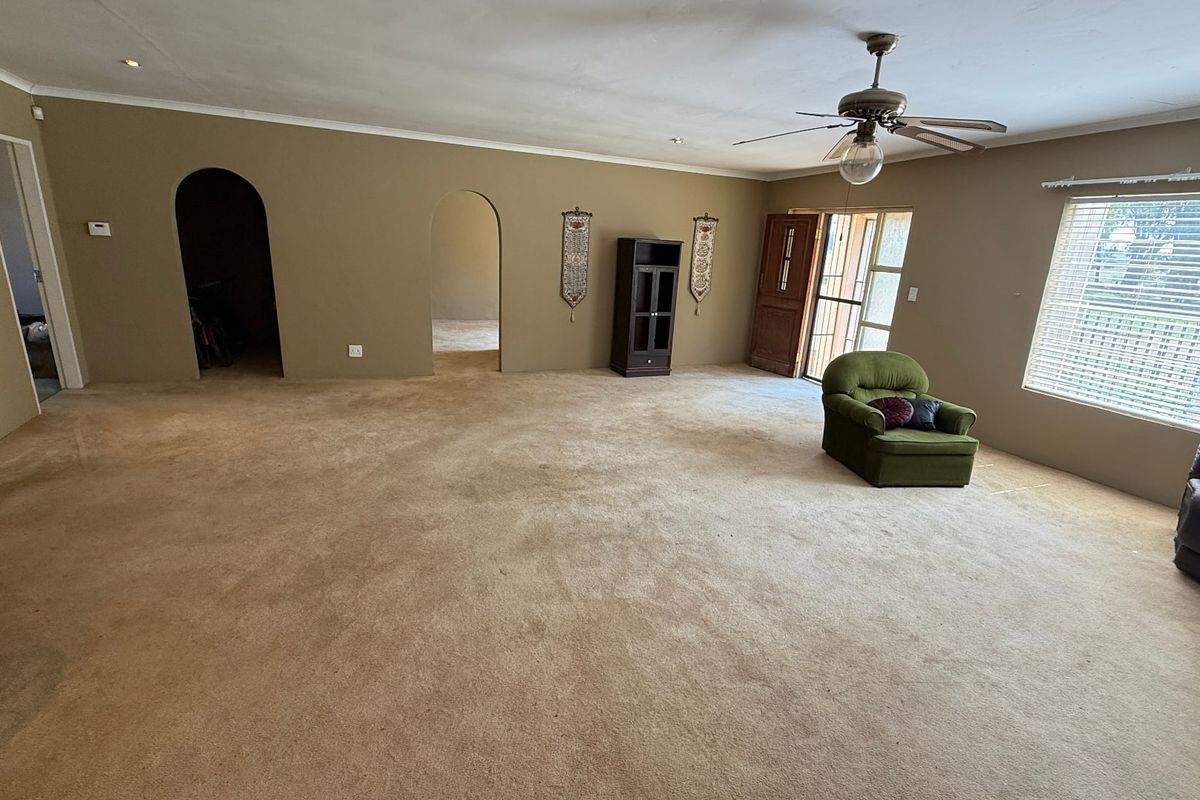 Spacious living room featuring arched doorways, neutral wall tones, and a ceiling fan, offering a versatile layout for comfortable family living.