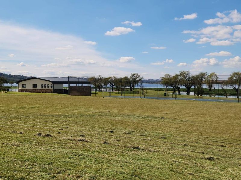 Expansive residential land featuring a sports court, outbuilding, and scenic waterfront views, offering significant potential for development or recreational use.