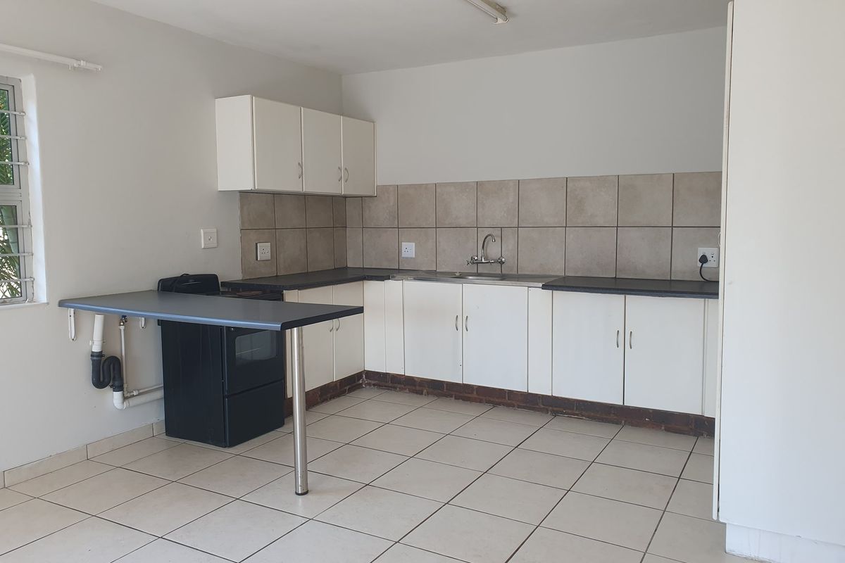 A functional kitchen featuring white cabinetry, tiled backsplash, laminate countertops, and tiled flooring, providing a clean and practical workspace.