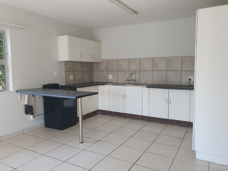 A functional kitchen featuring white cabinetry, tiled backsplash, laminate countertops, and tiled flooring, providing a clean and practical workspace.