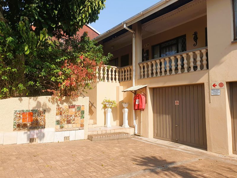 Front exterior view of the property featuring a paved driveway, garage access, and a balcony with decorative balustrades.