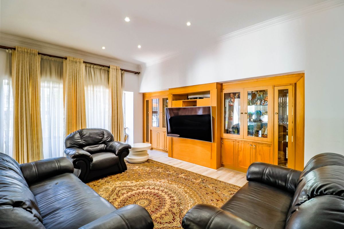 A living room featuring extensive built-in wooden cabinetry and recessed lighting, offering a functional space with classic architectural finishes.