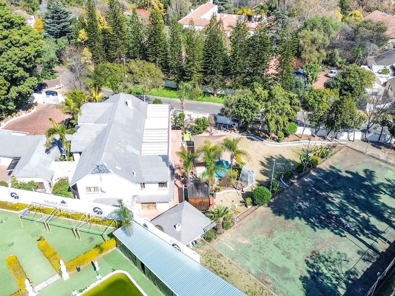 Aerial view of a large residential property featuring a swimming pool, tennis court, and extensive landscaped grounds.