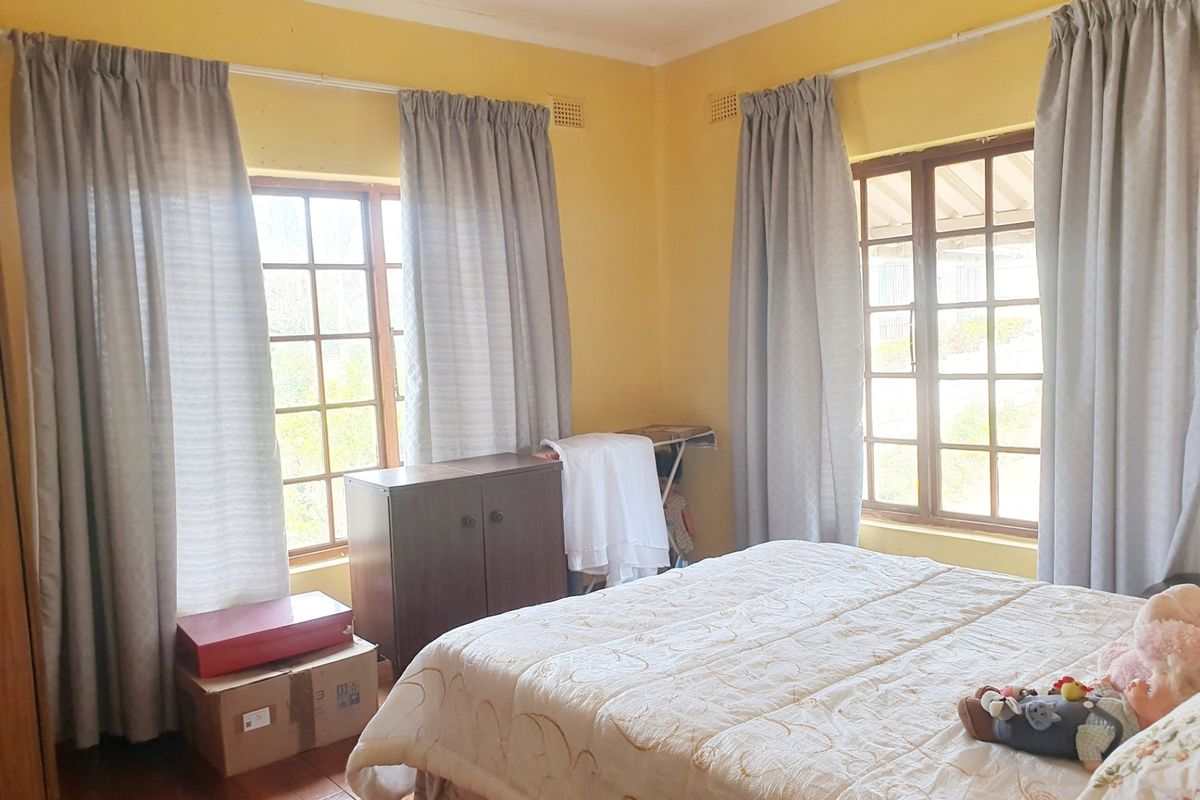 A bedroom featuring wooden window frames, recessed ceiling lighting, and wooden flooring, offering a functional space with potential for cosmetic updates.