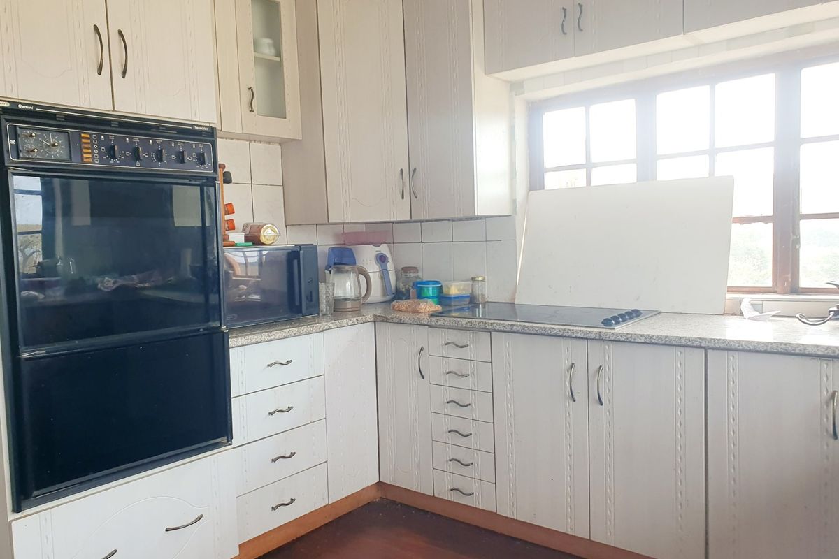 A functional kitchen featuring built-in oven, electric hob, ample cabinetry, and tiled backsplash, offering a classic layout ready for modern updates.