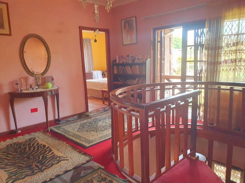 Upper level landing area featuring a wooden spiral staircase railing and access to an outdoor balcony through a sliding glass door.