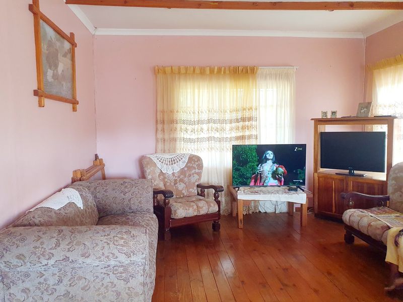 A living room featuring exposed timber ceiling beams and polished timber flooring, providing a traditional foundation for potential modern updates.