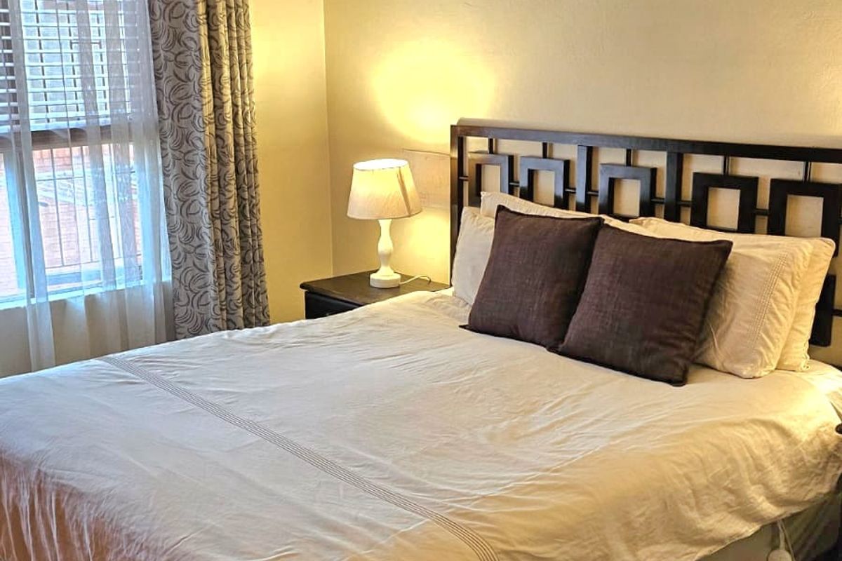 A well-lit bedroom featuring neutral wall tones, carpeted flooring, and decorative coving, providing a comfortable and functional sleeping space.