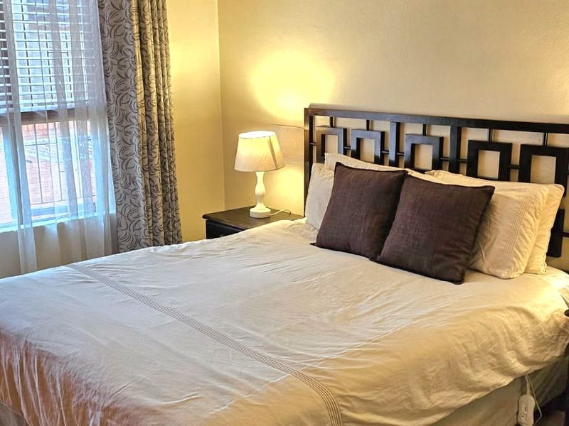 A well-lit bedroom featuring neutral wall tones, carpeted flooring, and decorative coving, providing a comfortable and functional sleeping space.