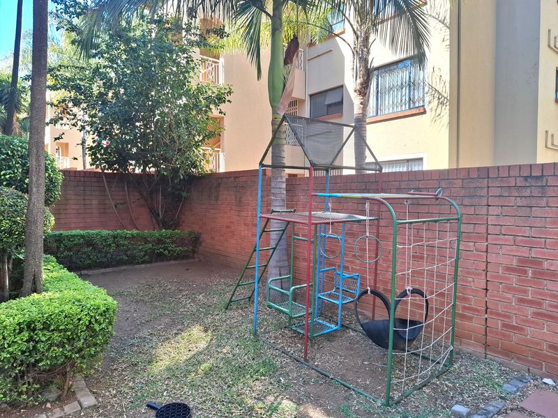 A private rear garden area featuring a brick boundary wall, established landscaping, and mature palm trees.