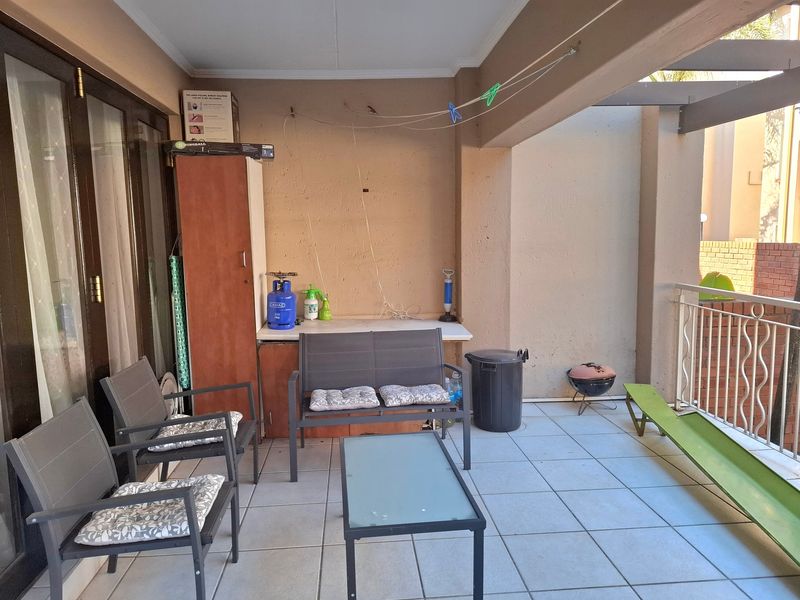 Covered patio area featuring tiled flooring, a metal balustrade, and a built-in storage cabinet with a fixed countertop.